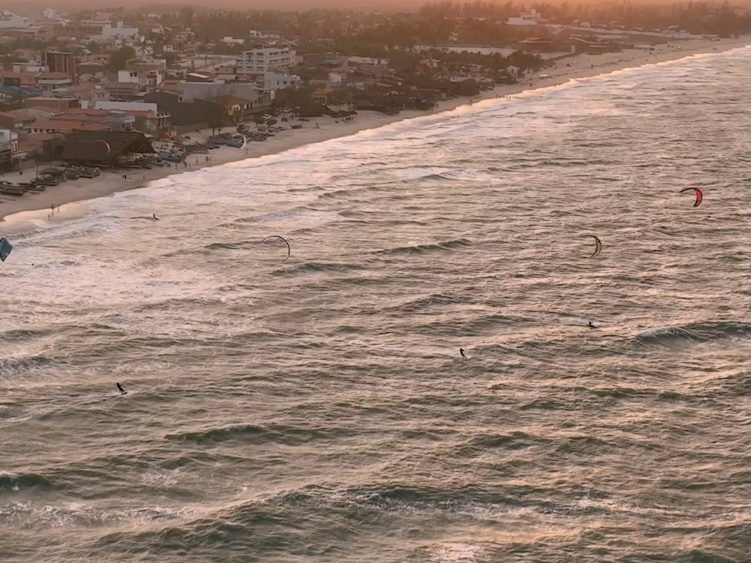Varias cometas navegando entre olas frente a Préa al atardecer