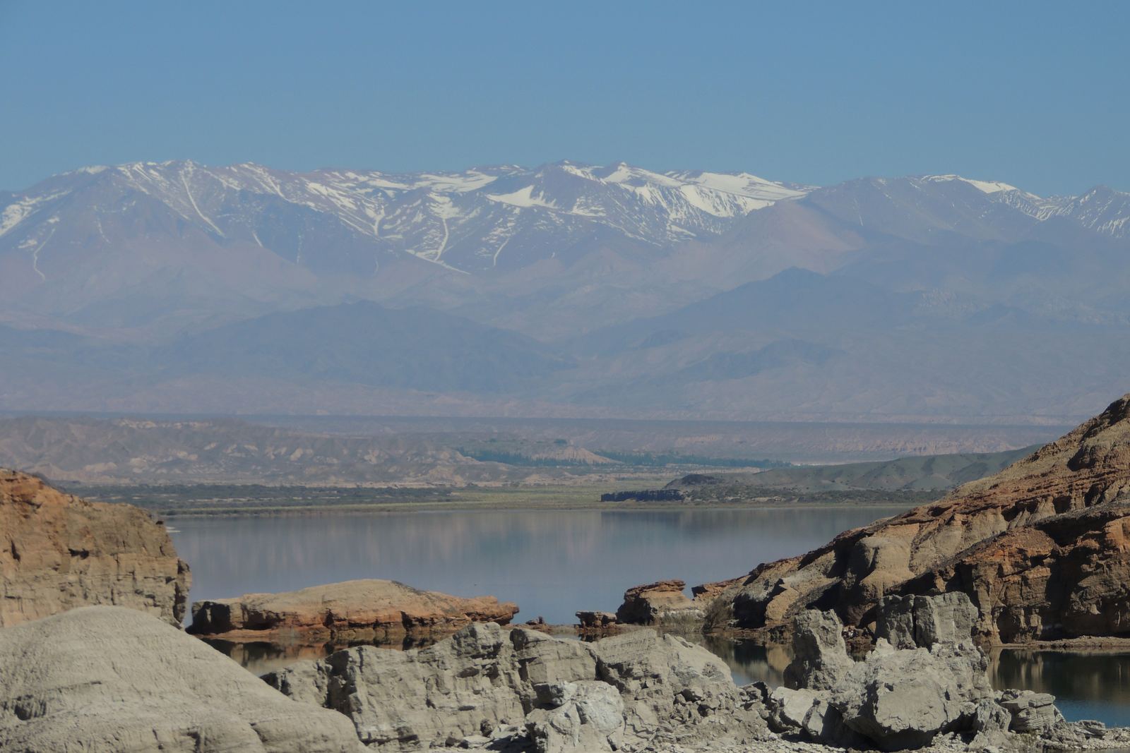 El embalse Cuesta del Viento en calma, con la cordillera nevada de San Juan al fondo