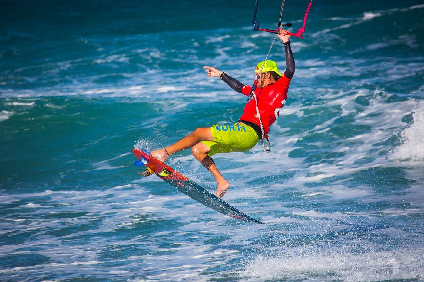 Kitesurfista haciendo un giro sobre agua turquesa