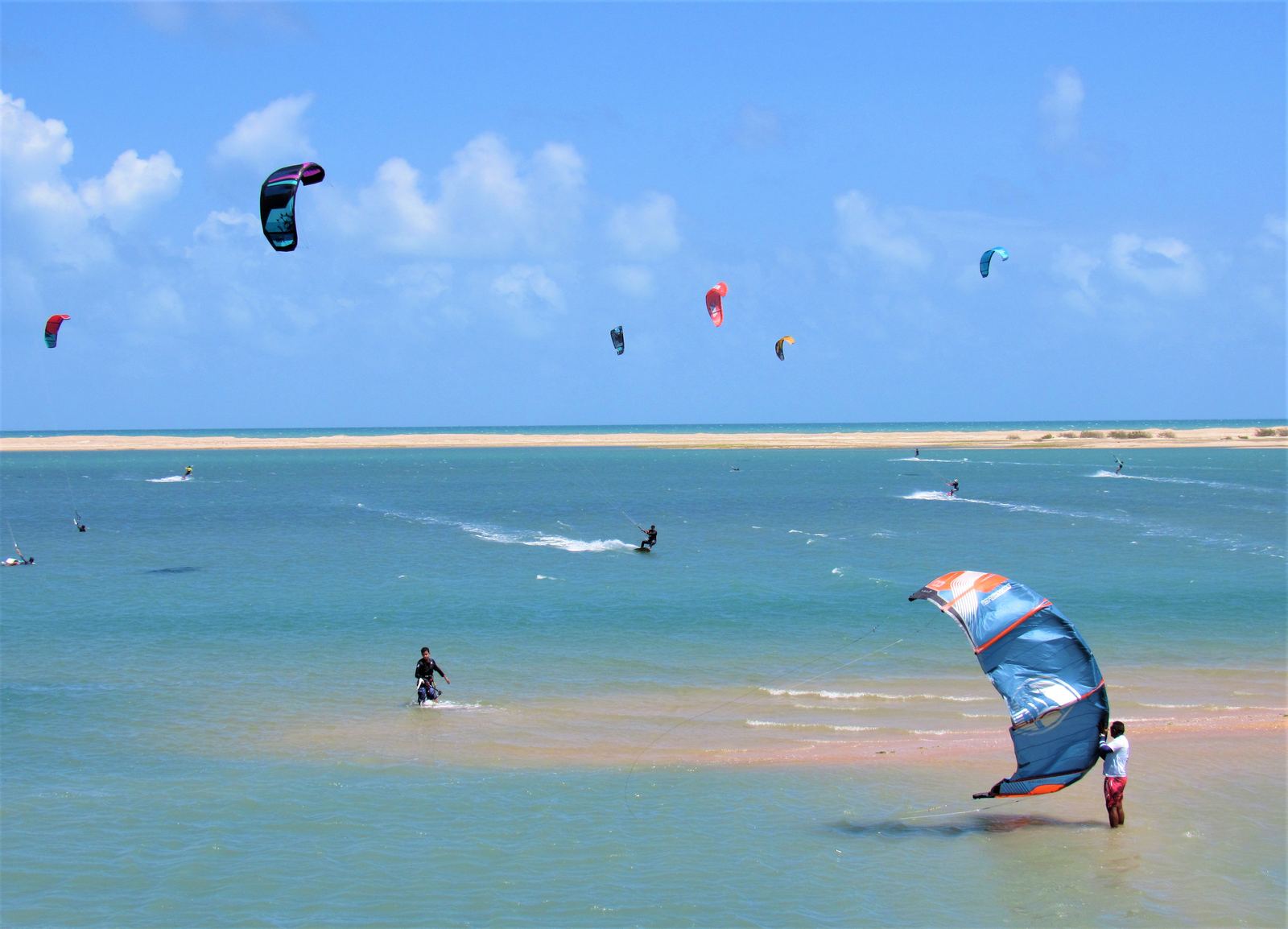 Varios kites navegando sobre el agua plana y turquesa de la costa de Ceará