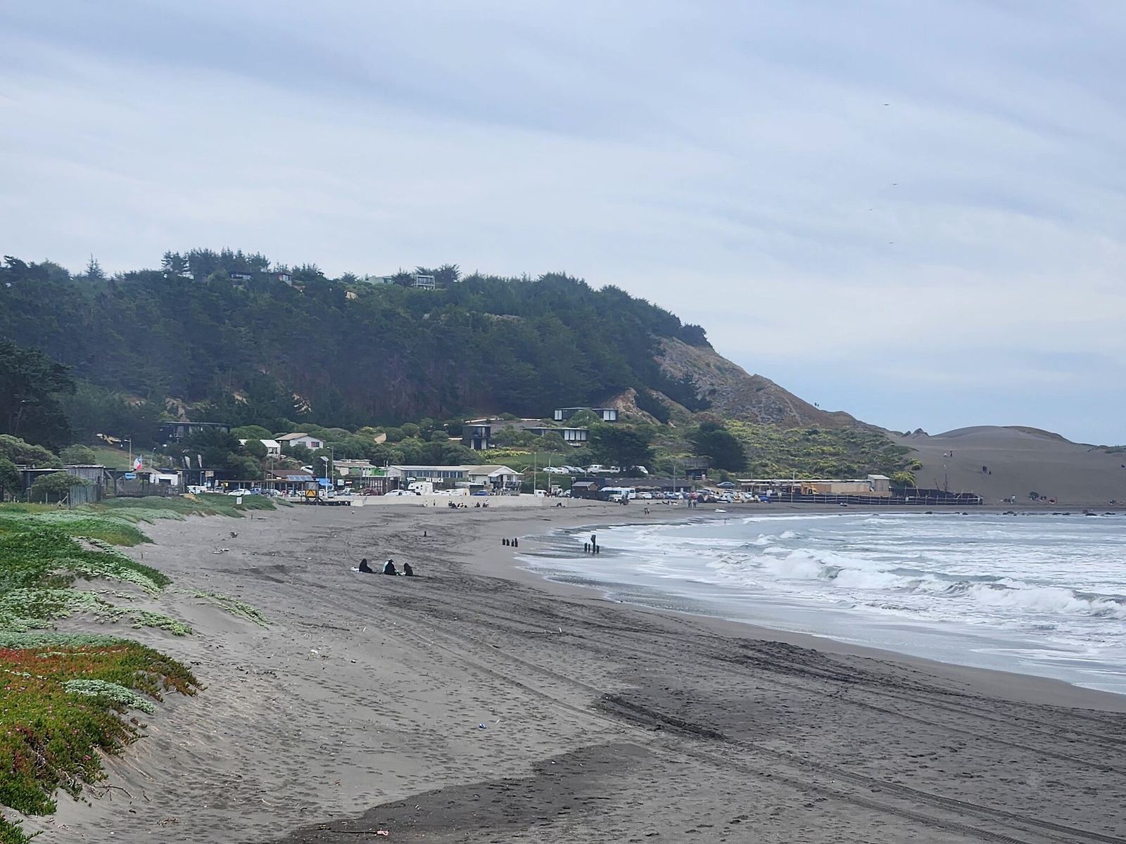 Playa de Matanzas, en la comuna de Navidad, con oleaje y el pueblo sobre la ladera