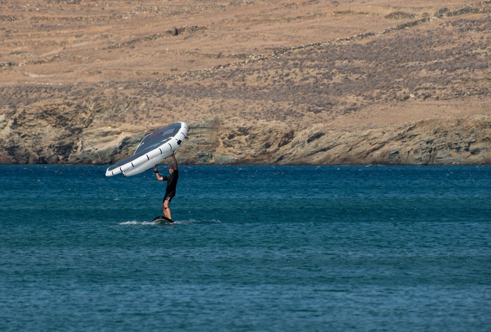 Rider navegando con un wing de mano sobre una tabla con hydrofoil